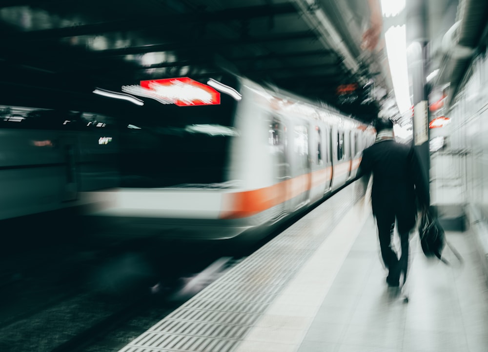 man in black jacket standing beside white train