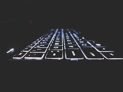 Close-up of hands typing on a sleek keyboard with futuristic lighting.