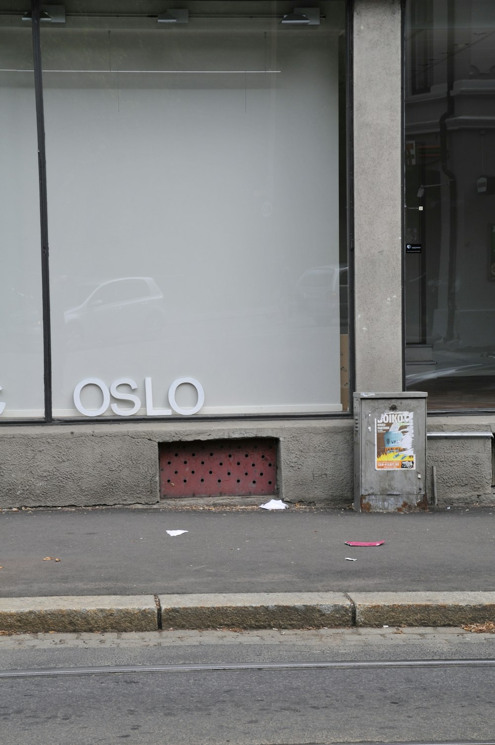 white and black trash bin beside gray concrete wall