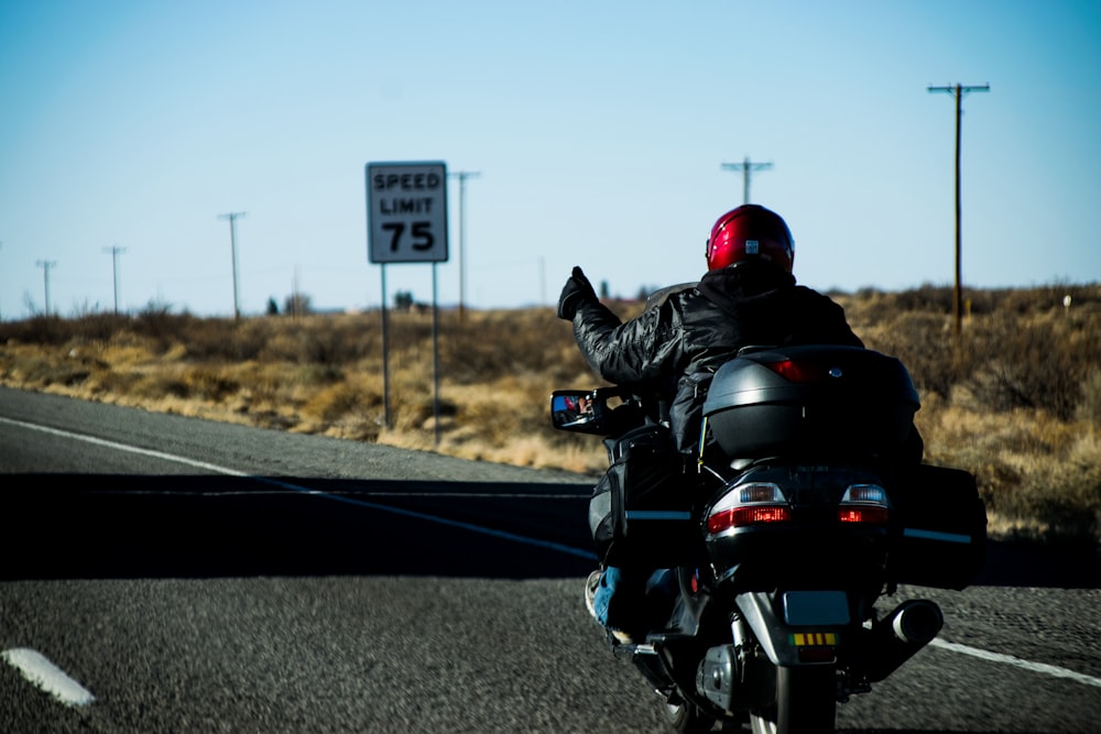 man in black leather jacket riding motorcycle on road during daytime