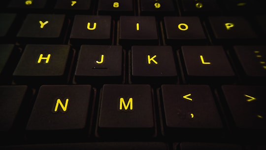 Close-up of hands typing on a keyboard with yellow accents in the background.