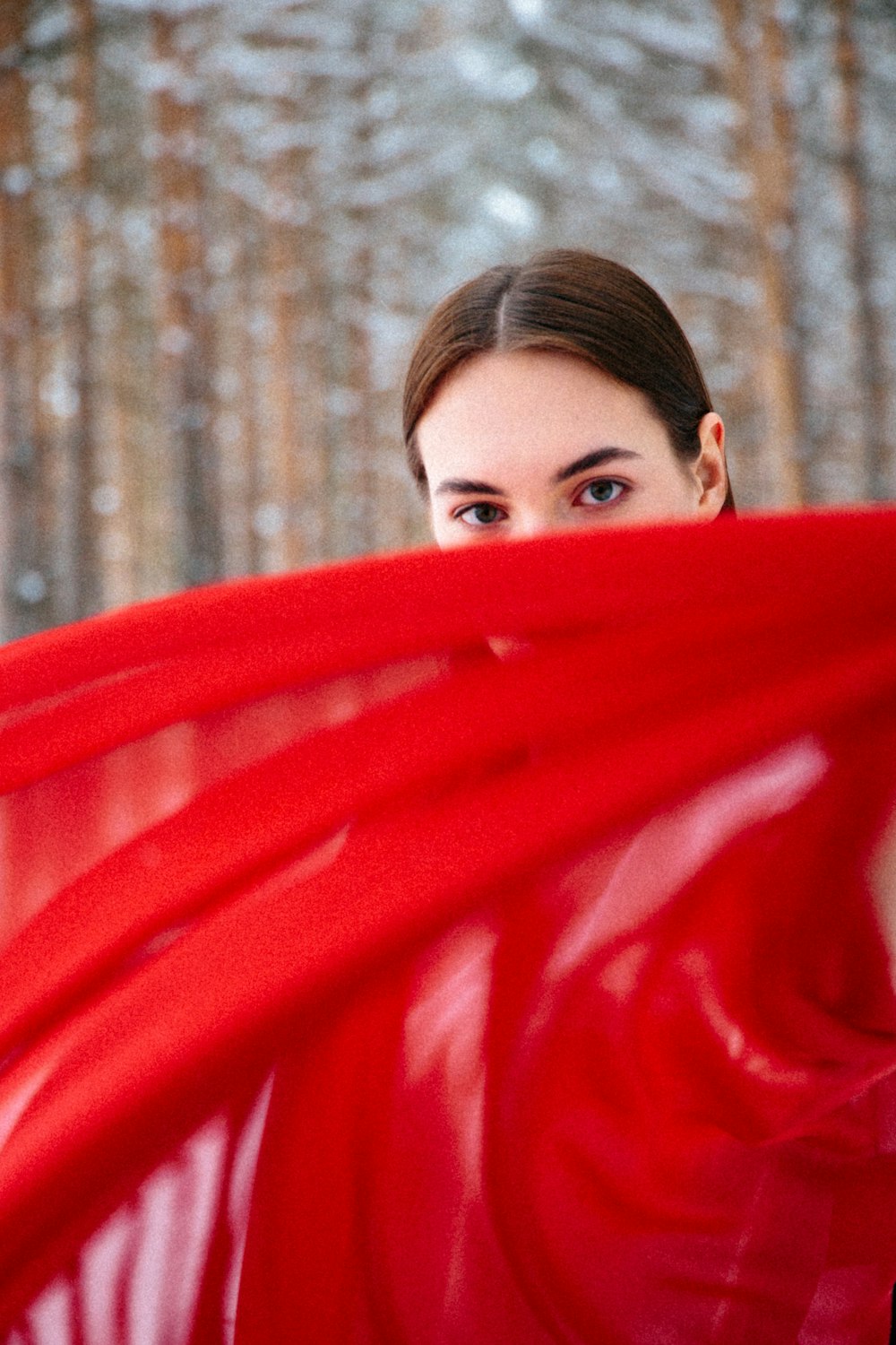woman in red scarf standing near brown trees during daytime