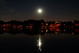 A glowing full moon rising over a tranquil lake, reflecting shimmering light.
