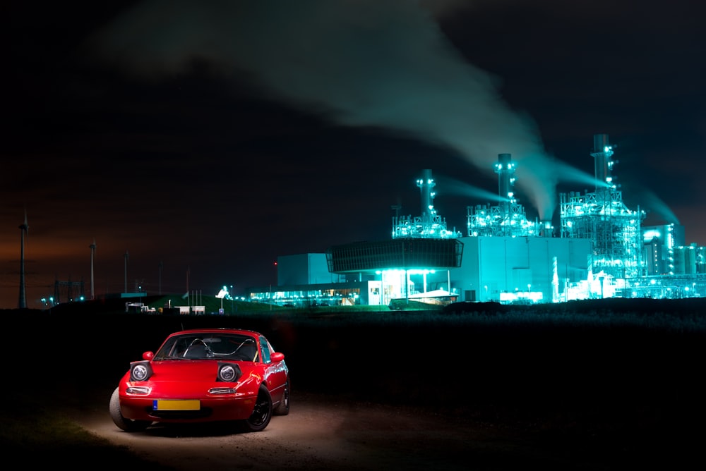 red sedan parked near green building during night time