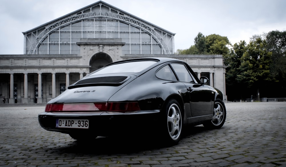 Schwarz-roter Porsche 911 parkt in der Nähe des weißen Gebäudes