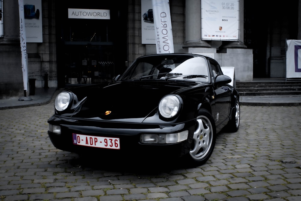Schwarzer Porsche 911 auf grauem Ziegelboden geparkt