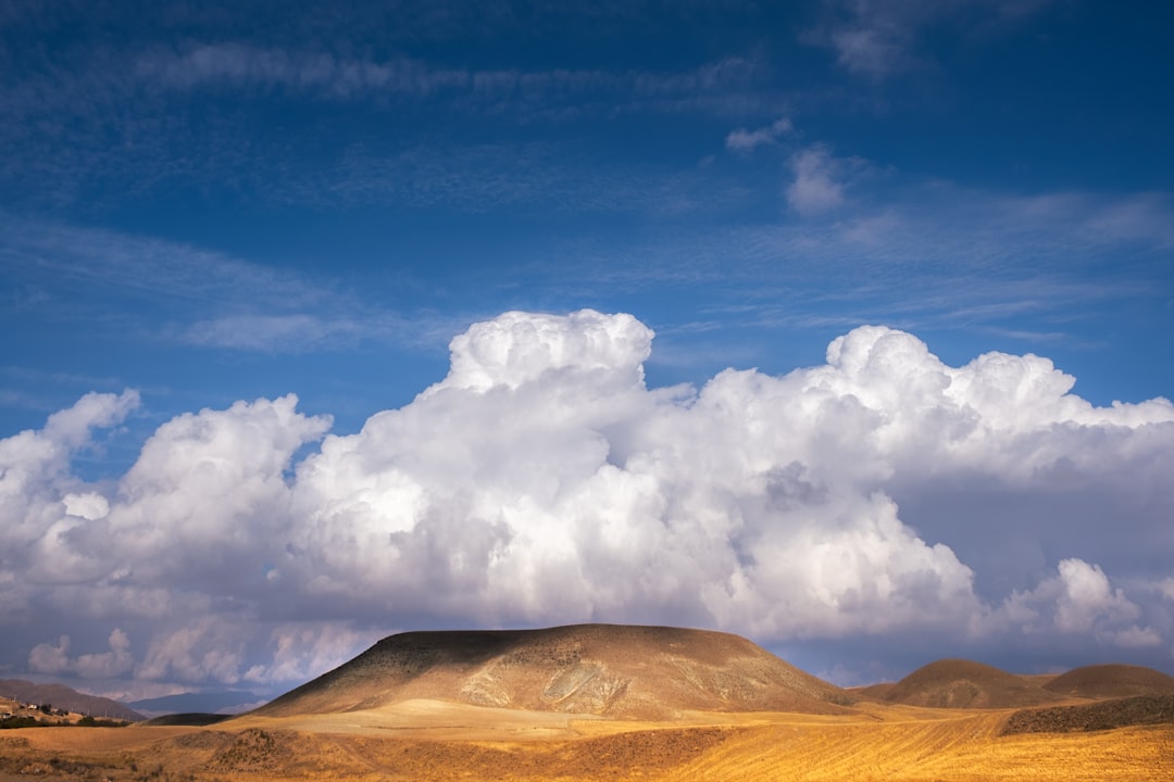 brown mountain under white clouds and blue sky during daytime