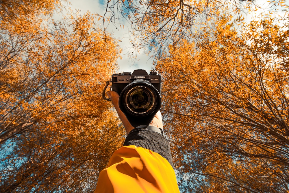 person in yellow jacket holding black dslr camera