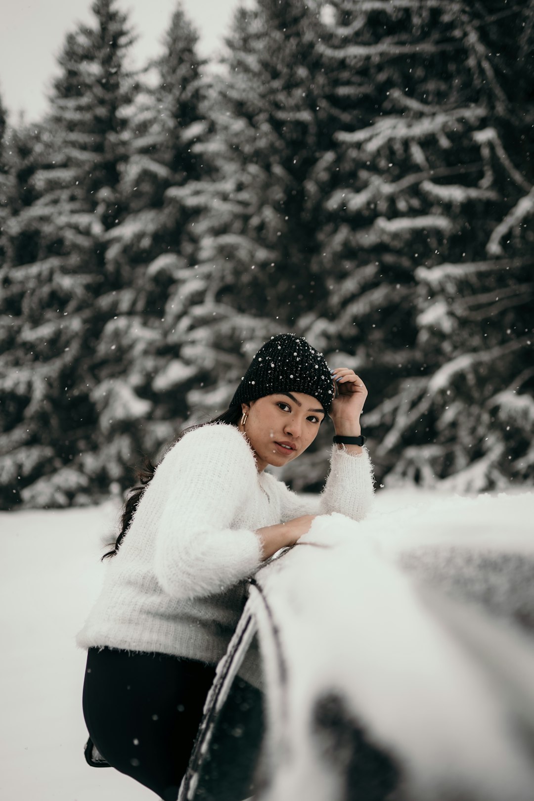 woman in white sweater and black knit cap standing on snow covered ground during daytime