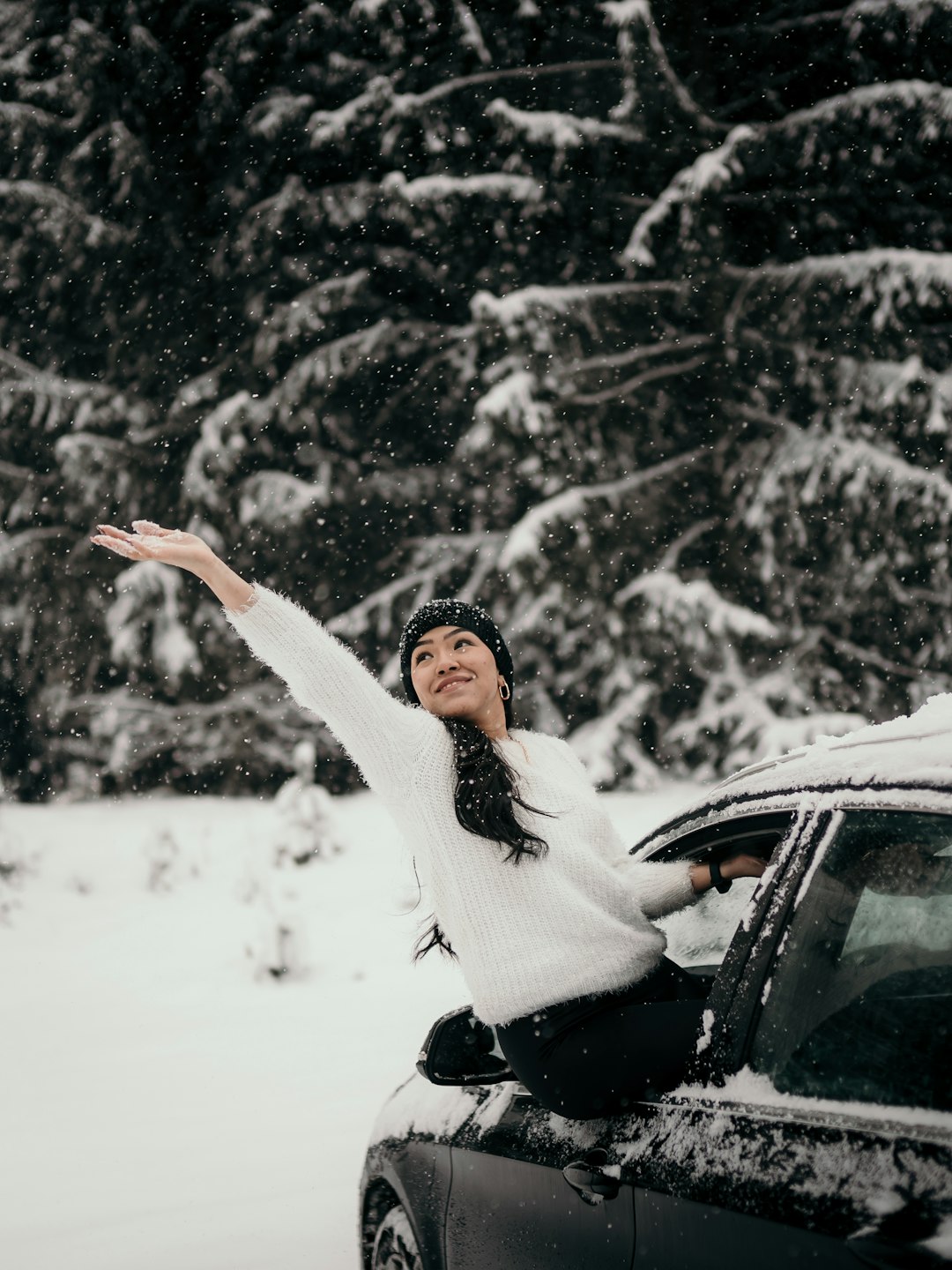 woman in white sweater and black pants sitting on snow covered ground during daytime