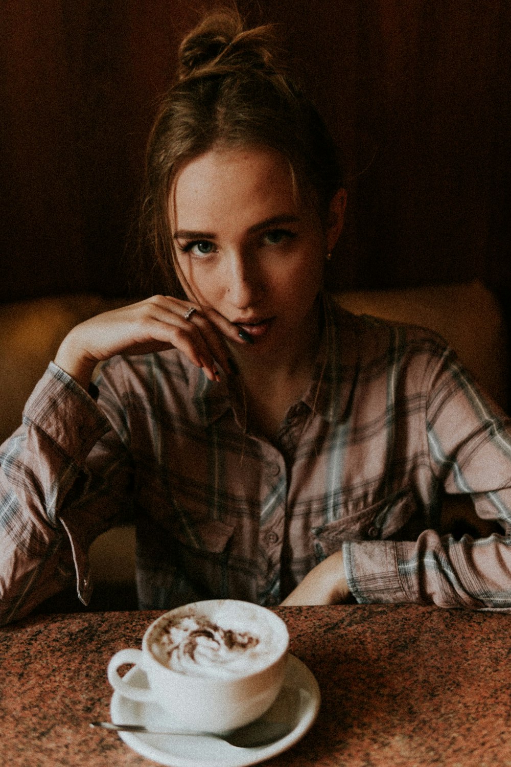 woman in brown and white plaid dress shirt sitting on chair