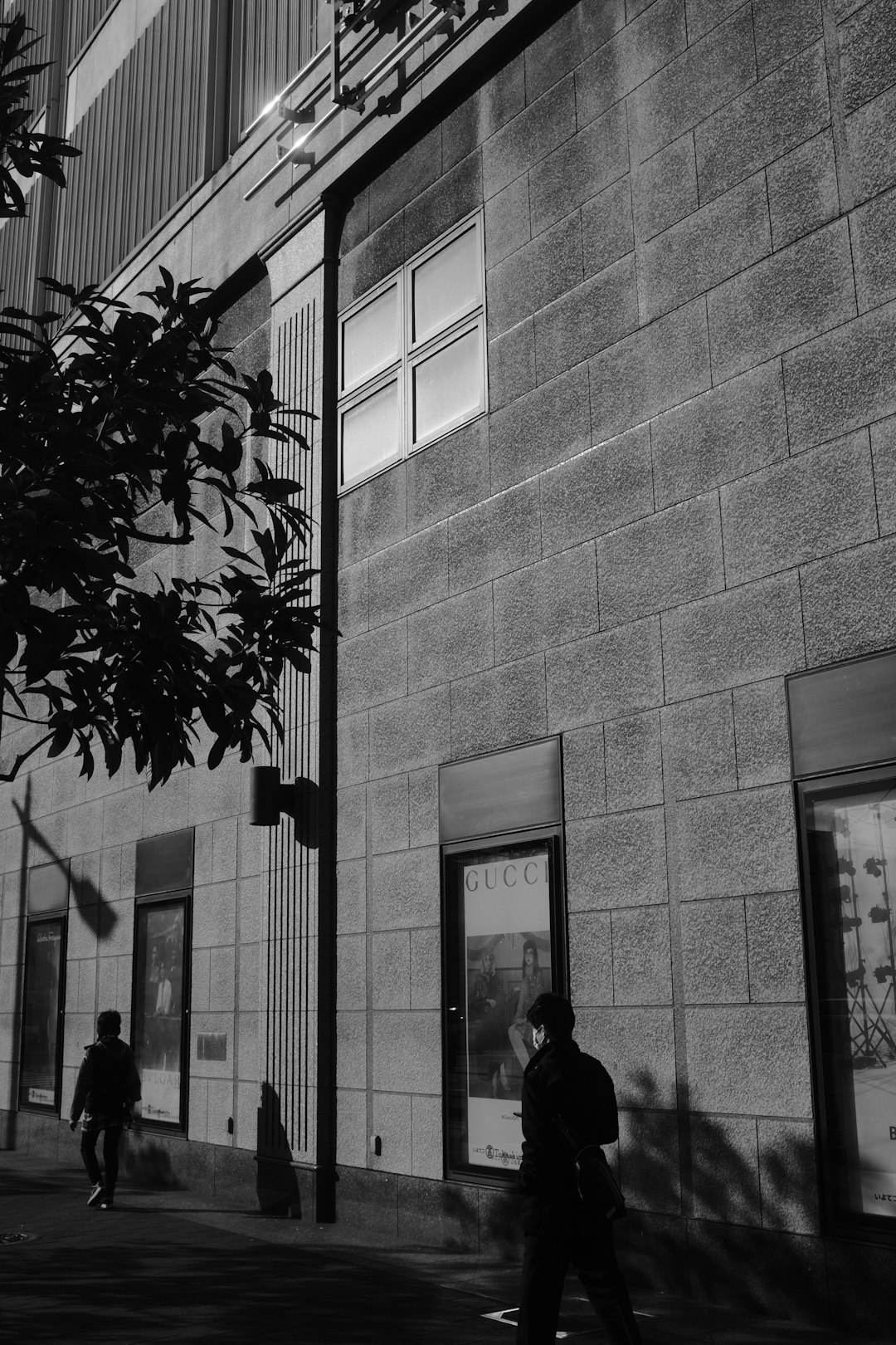 grayscale photo of man and woman standing near building