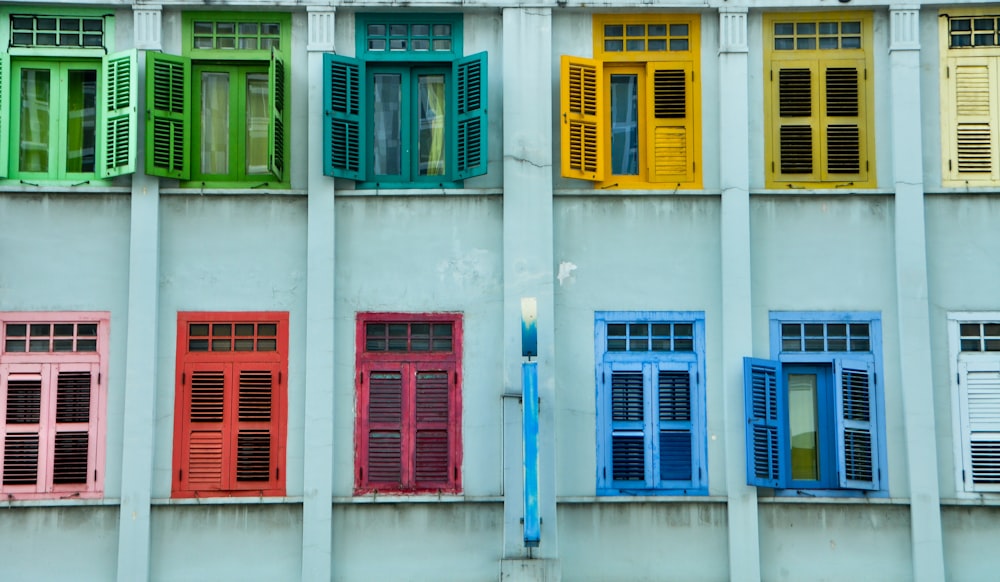 red and blue wooden windows on white concrete building