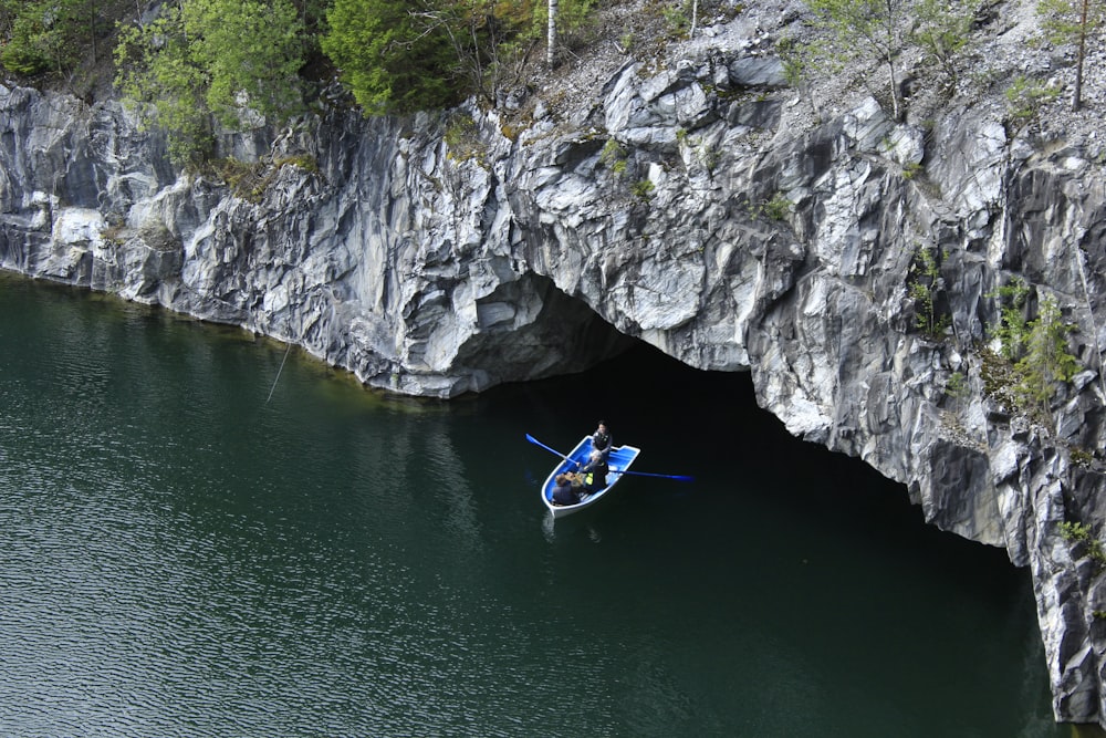 man in blue kayak on river near gray rocky mountain during daytime