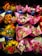 A variety of flower bouquets are arranged in buckets, each wrapped in colorful paper. The bouquets contain a mix of tulips, roses, and daisies, with some brightly colored papers and tags indicating prices.