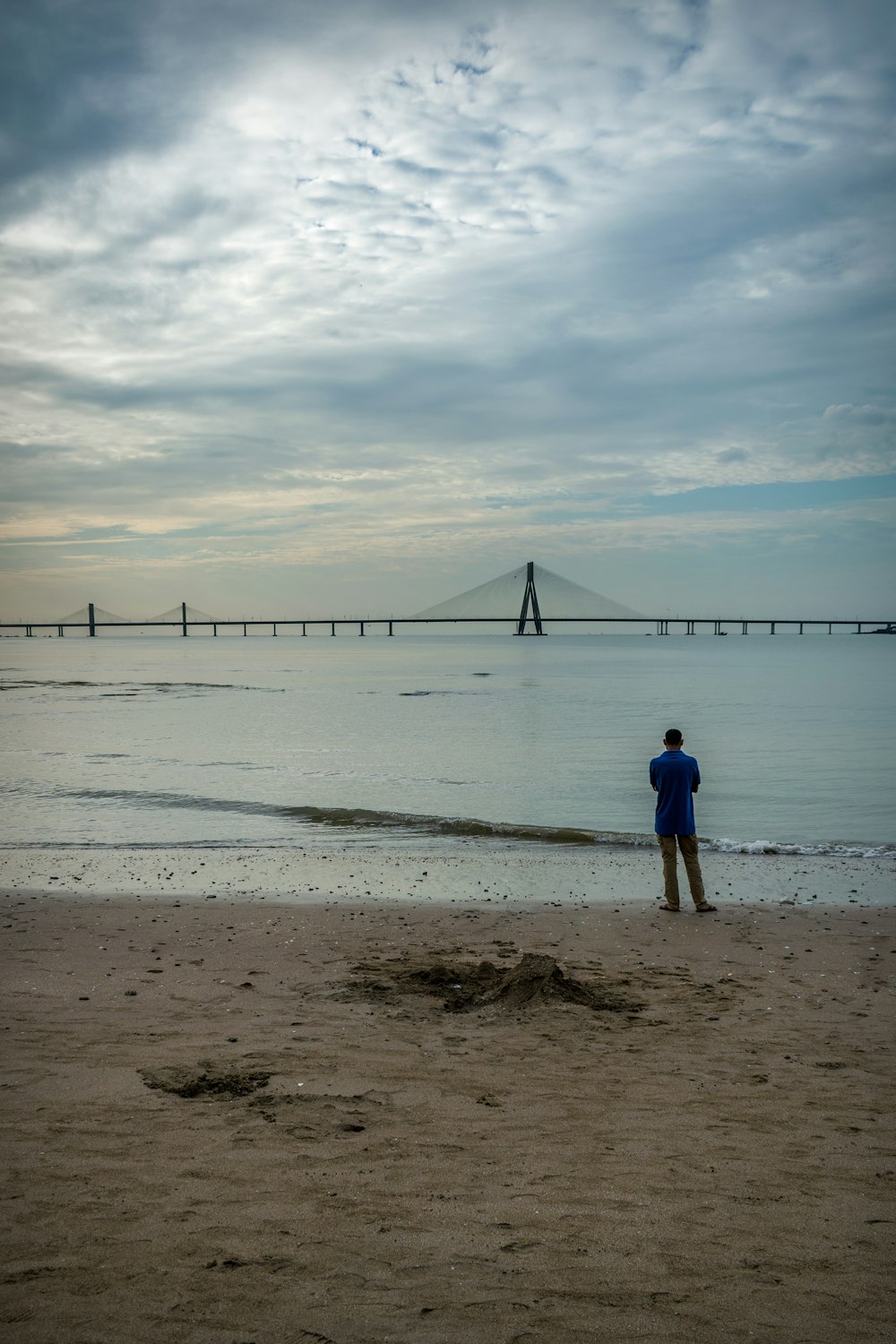 man in blue shirt walking on beach during daytime