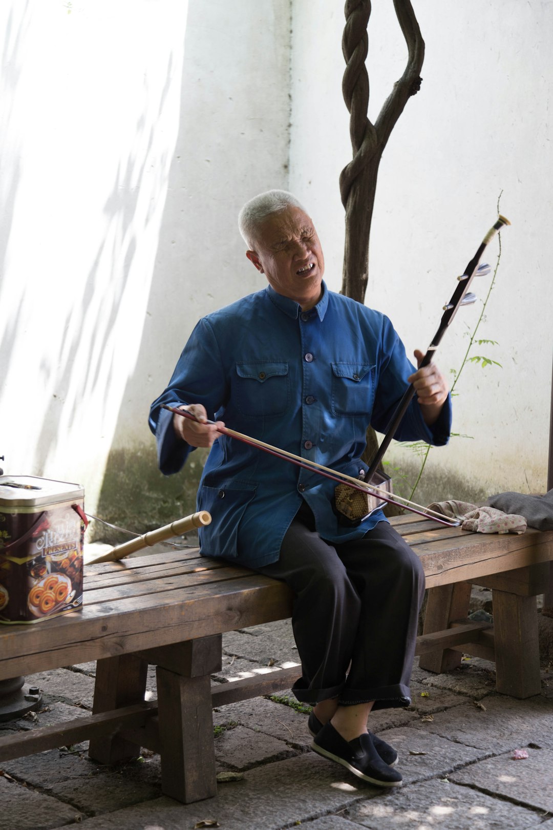 man in blue dress shirt and black pants sitting on brown wooden bench holding fishing rod