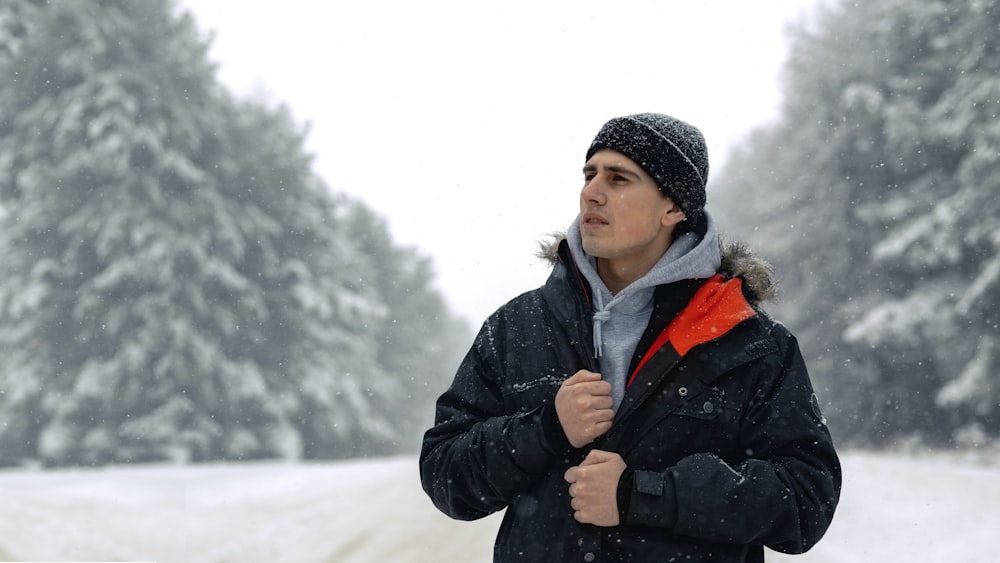 woman in black jacket and gray knit cap standing on snow covered ground during daytime