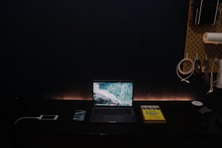 A minimalist workspace bathed in warm sand tones with a sleek charcoal grey laptop and ivory accents.