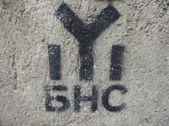 Black graffiti with Cyrillic characters is painted on a rough-textured concrete wall.