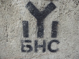 Black graffiti with Cyrillic characters is painted on a rough-textured concrete wall.