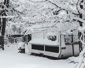 Technician performing winterization on an RV outdoors in a snowy setting.