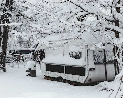 Technician performing winterization on an RV outdoors in a snowy setting.