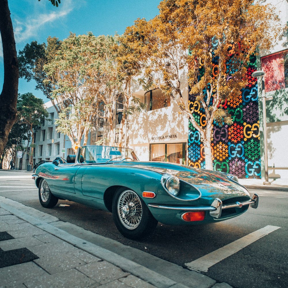 blue coupe parked on sidewalk during daytime