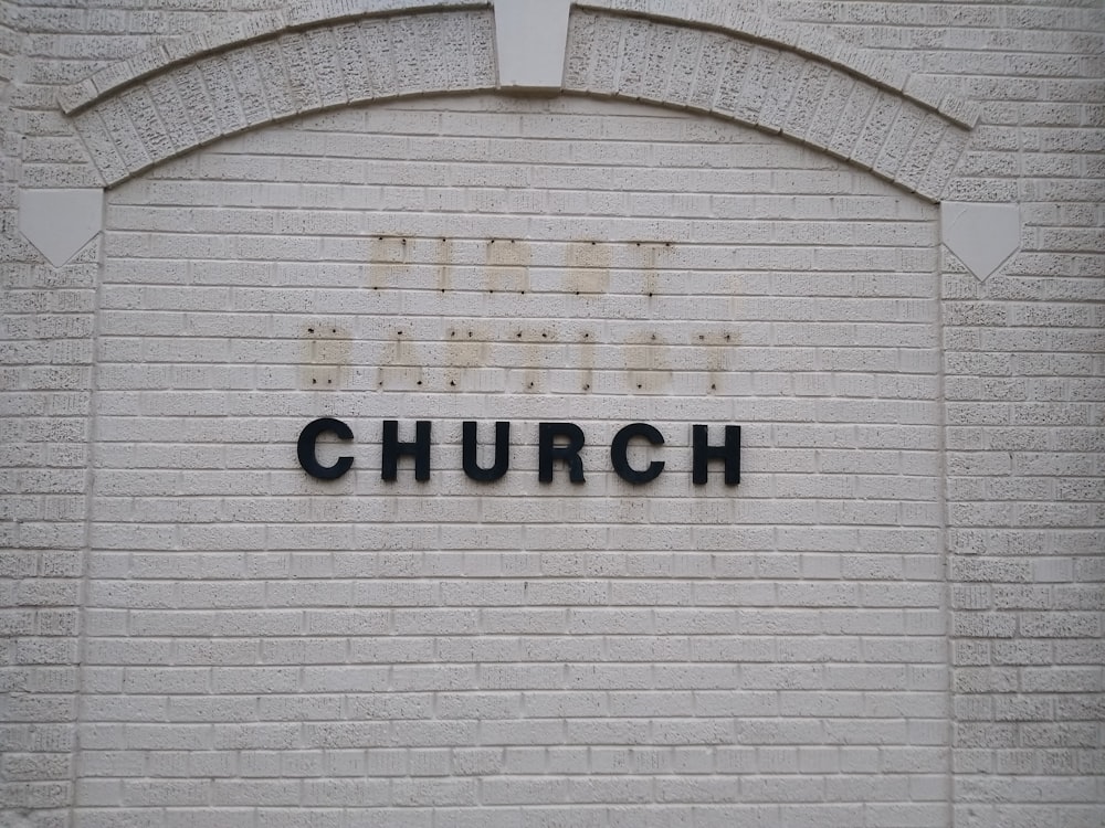 Una pared de ladrillo con un letrero que dice, la iglesia