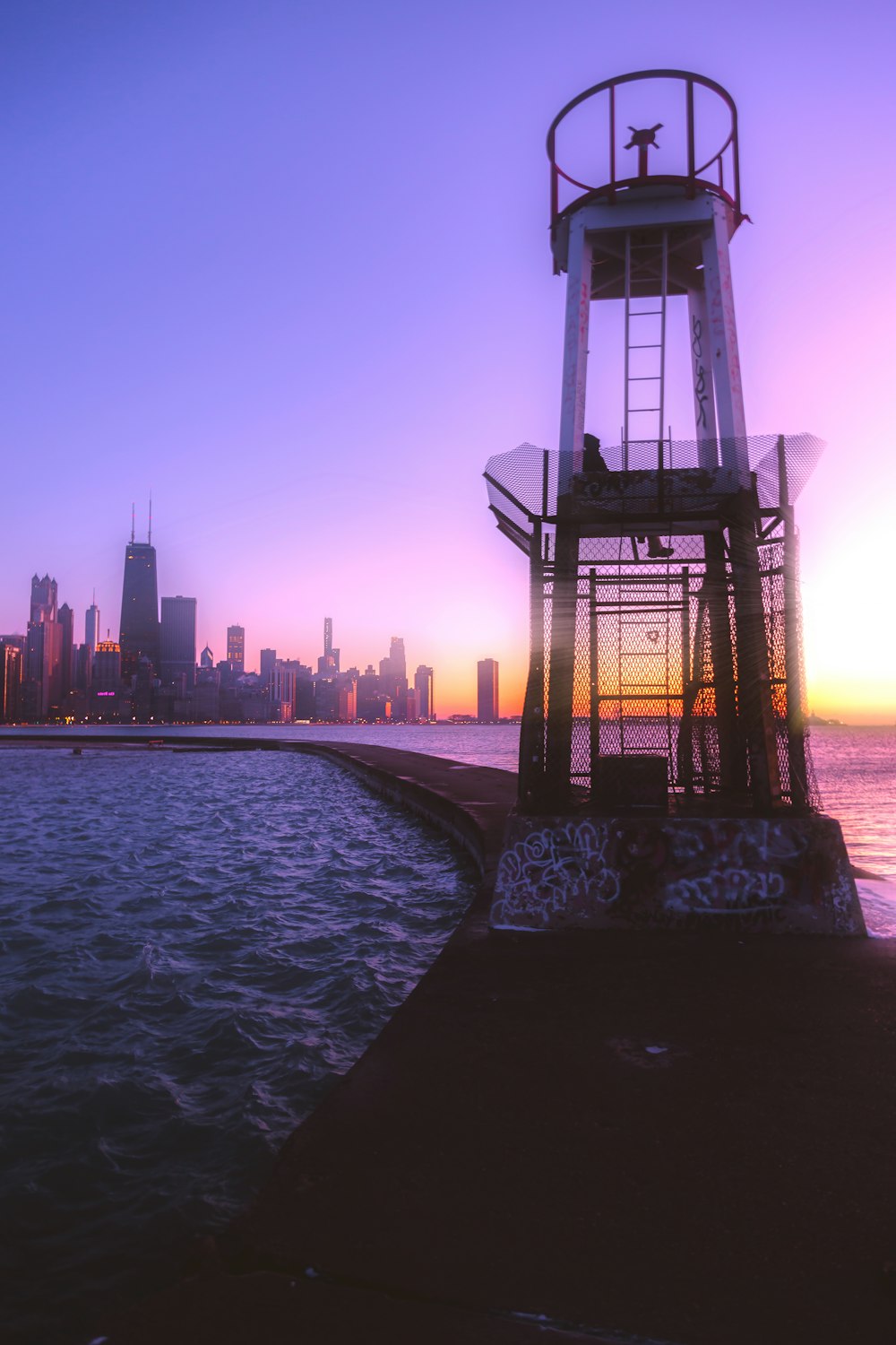 silhouette of tower near body of water during sunset