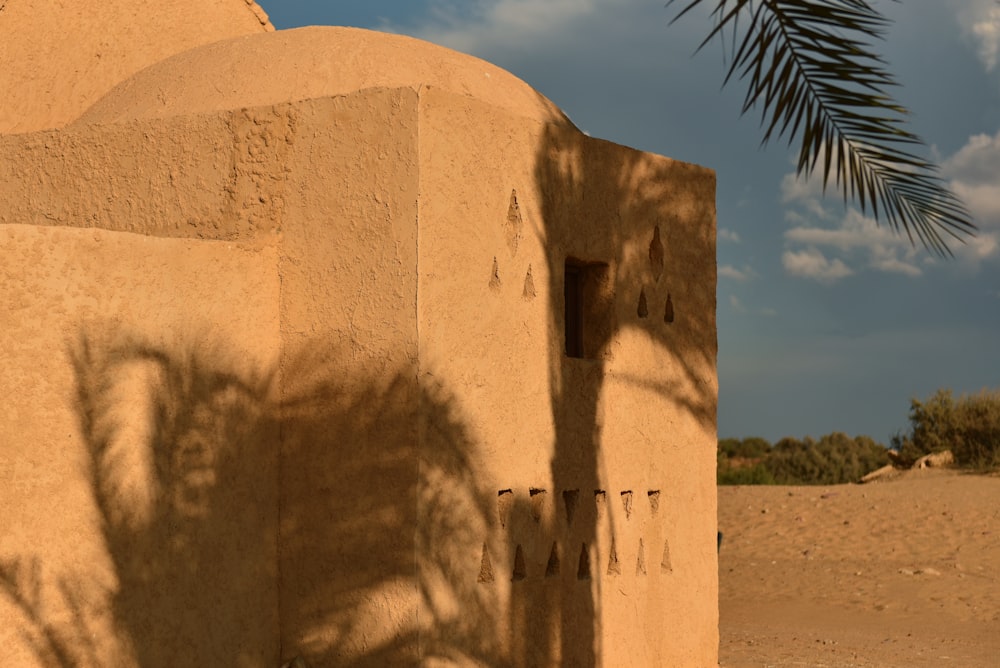 brown concrete building near green palm tree under blue sky during daytime