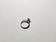 A minimalist silver ring catching soft light on a matte black background.