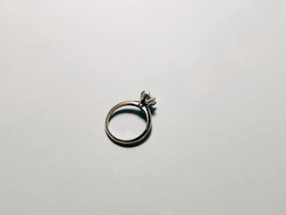 Close-up of a silver ring with a polished finish and subtle sparkle on a soft beige background