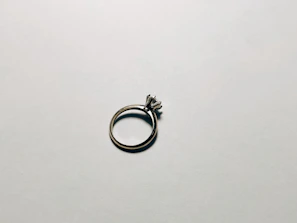 Close-up of a silver ring with a polished finish and subtle sparkle on a soft beige background