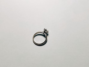 Close-up of a delicate silver ring with a soft pink background reflecting light warmly