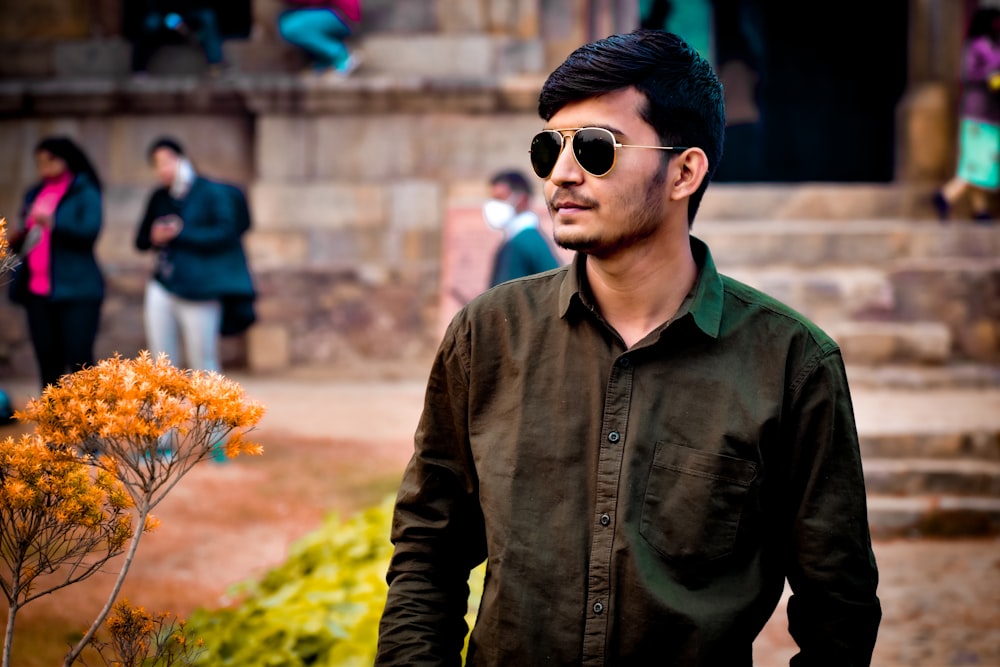 man in black button up jacket holding orange flower