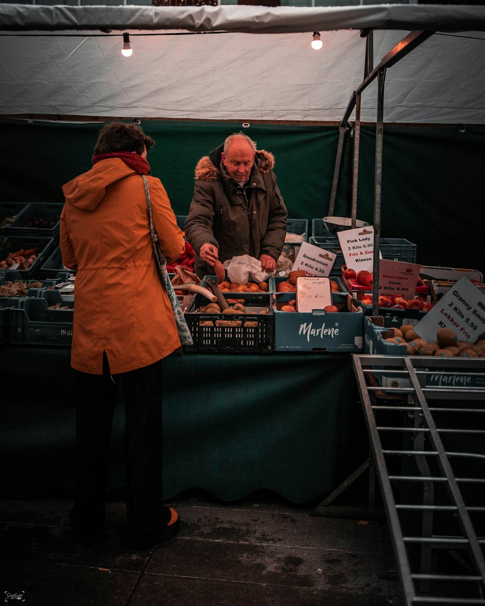 woman in orange coat standing in front of shopping cart