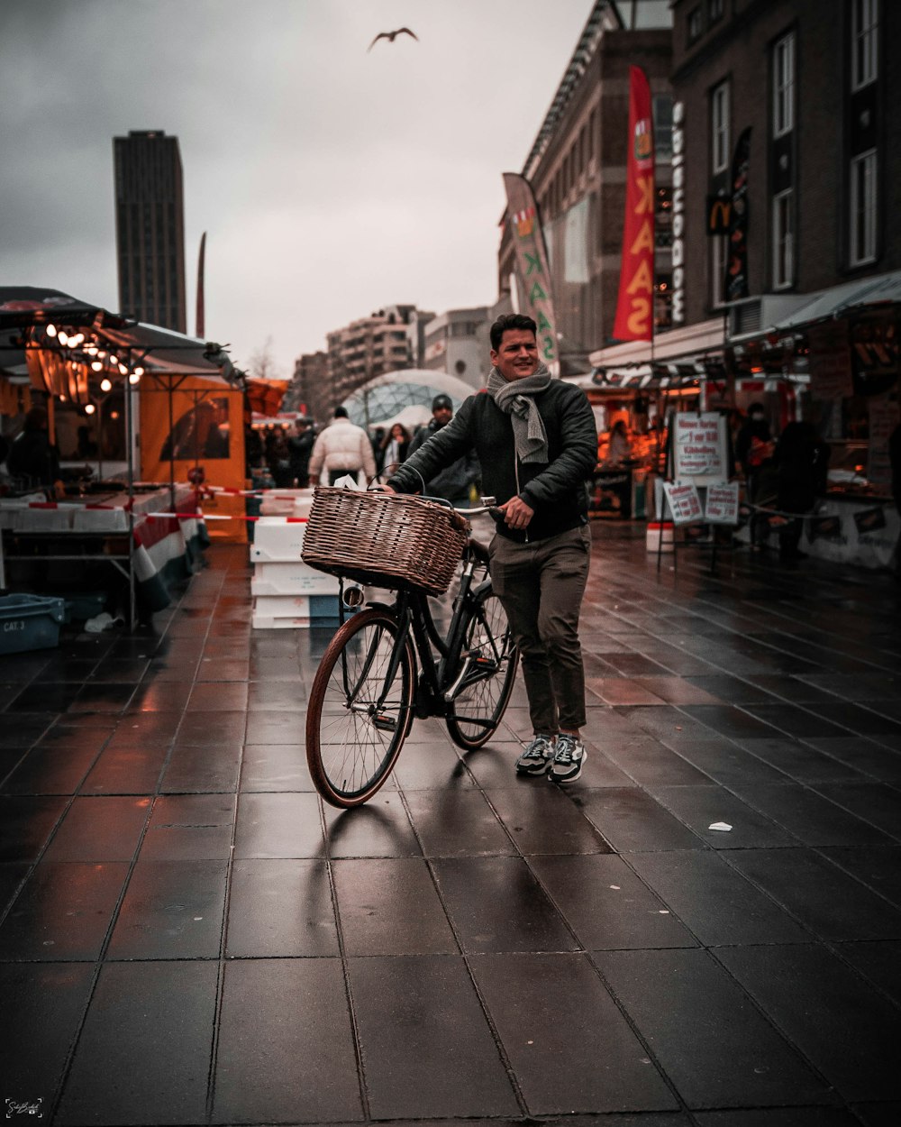 man in black jacket riding on black bicycle on street during daytime