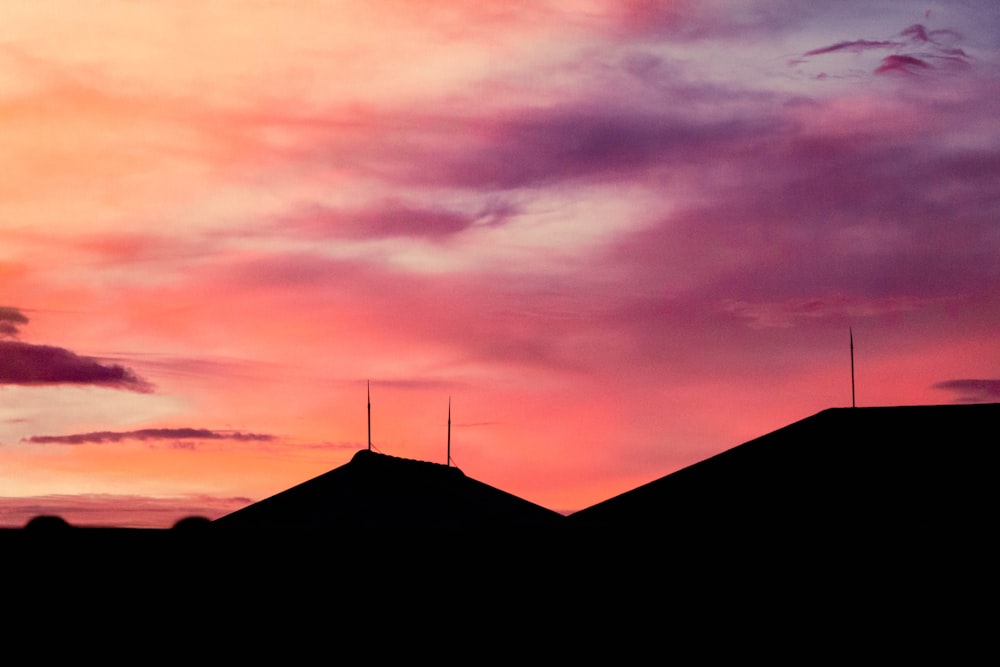 silhouette of house under orange and gray clouds