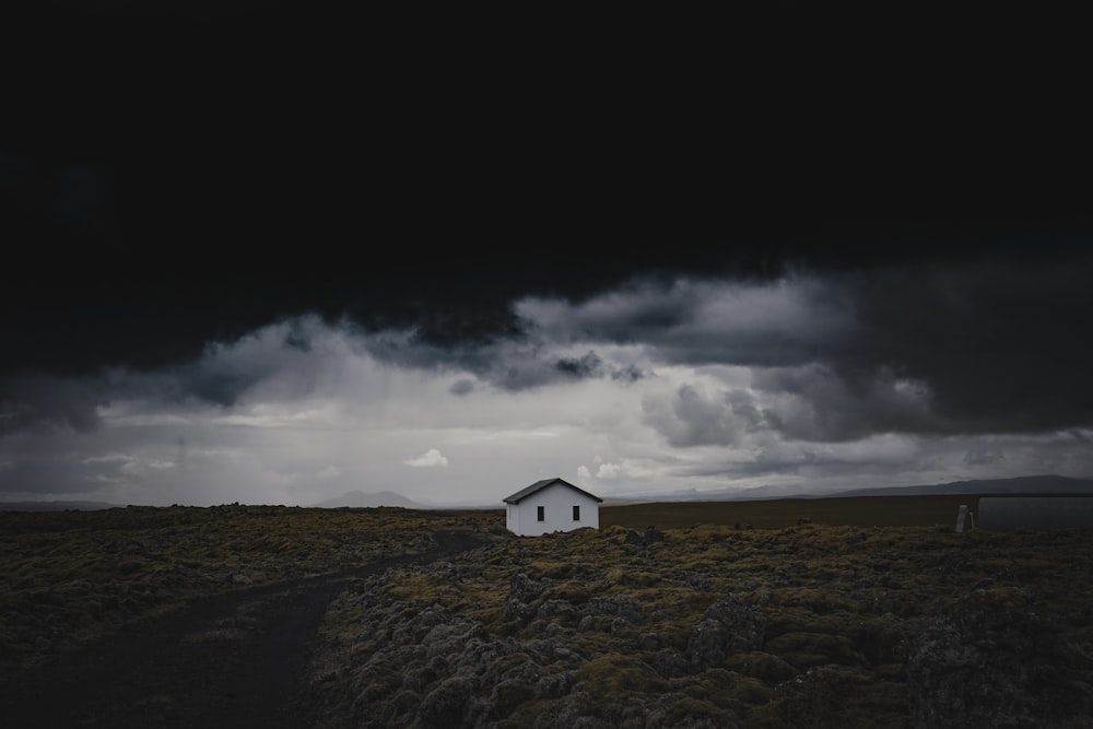 white and gray house on green grass field under gray clouds