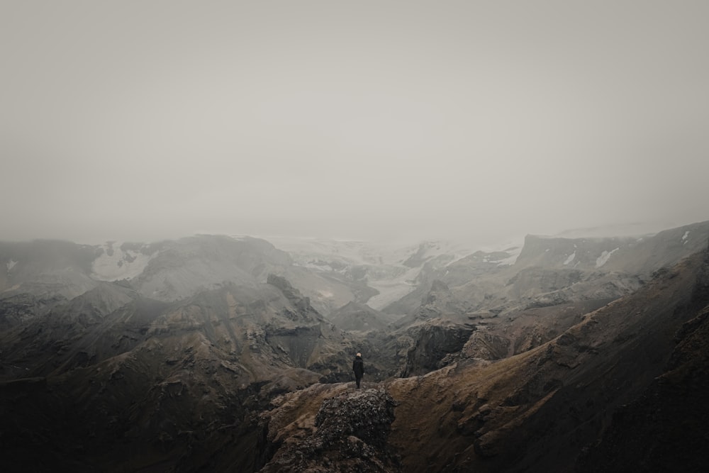 person in black jacket standing on brown rock mountain during daytime