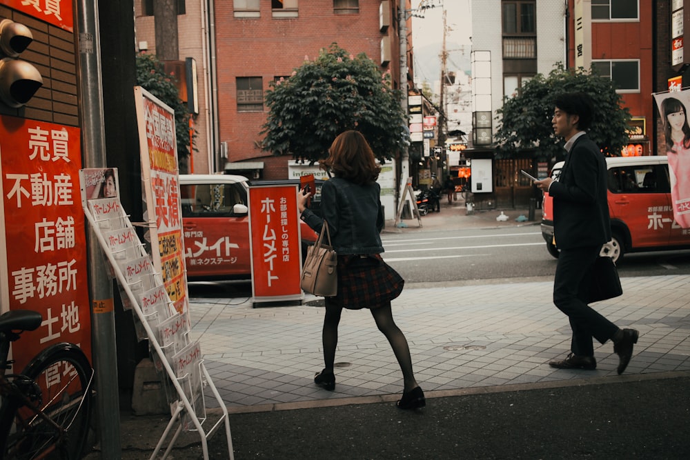 woman in black jacket walking on sidewalk during daytime