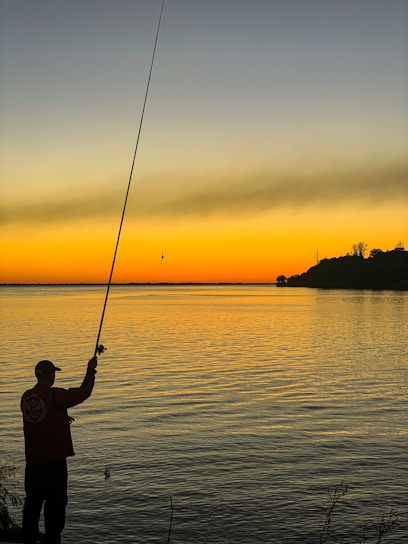 Fisherman casting a line into the calm waters of Rio Parada at sunset
