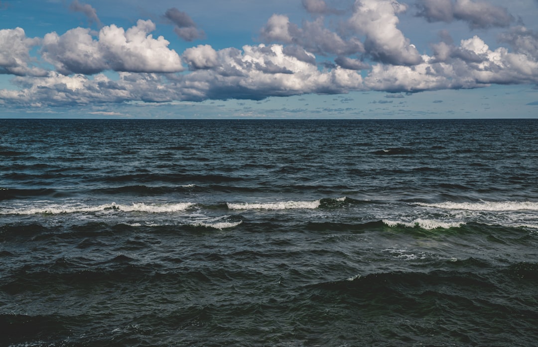 ocean waves under white clouds and blue sky during daytime