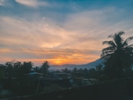 Sunset view over a property with tropical trees and mountains in the distance.