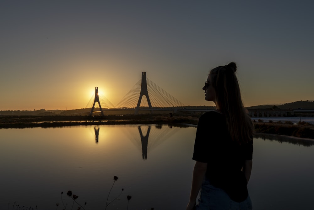 Silueta de mujer de pie en el muelle durante la puesta del sol