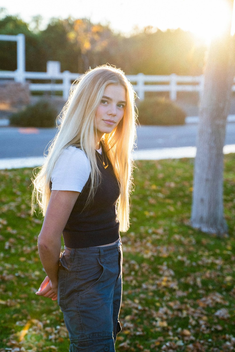 woman in black t-shirt and blue denim shorts standing on green grass field during daytime