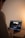 A person is seated at a wooden desk, focused on editing a video. The open laptop screen displays video editing software featuring various tools and timeline sections. The lighting is soft and warm, creating a relaxed ambiance.
