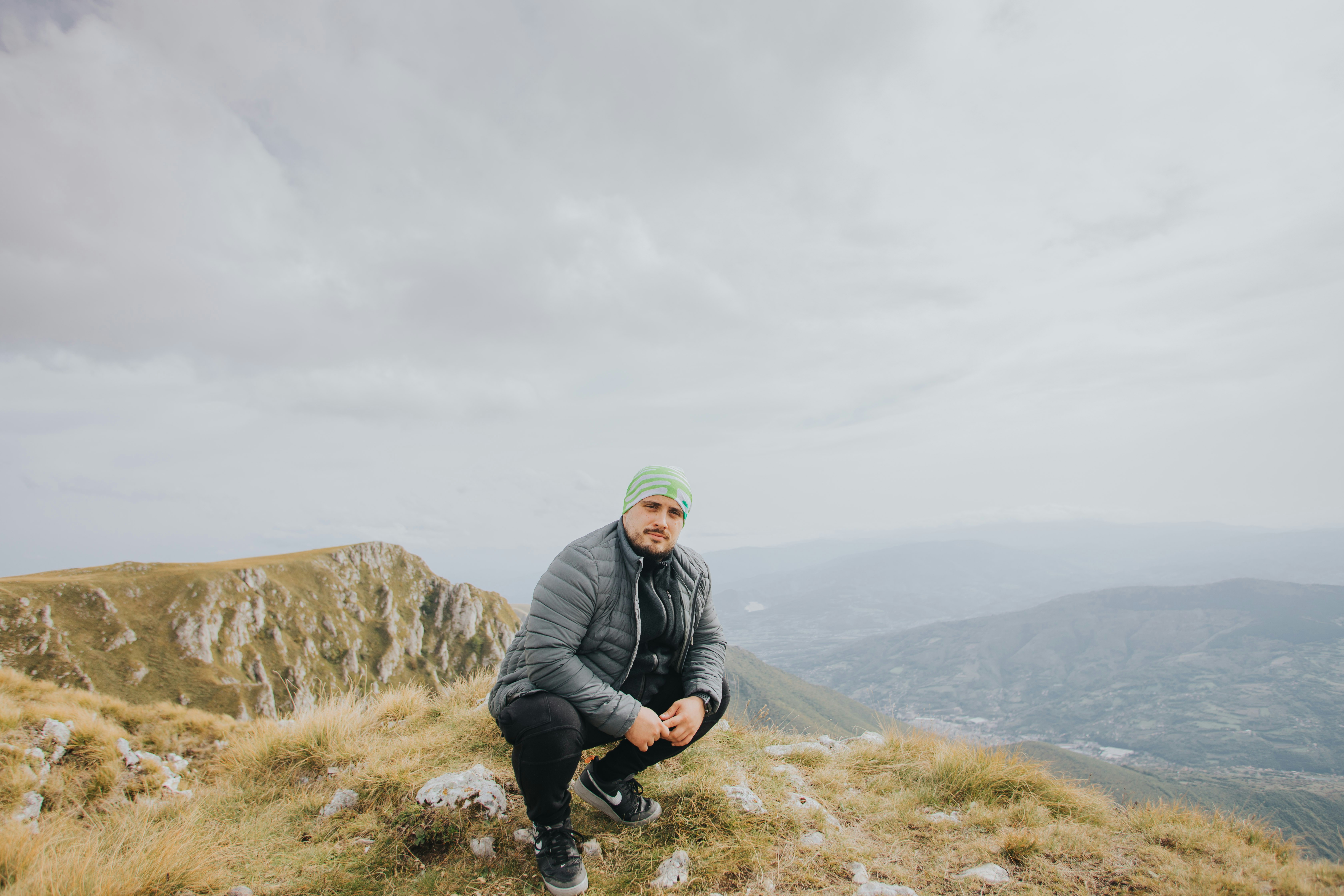 man in black jacket sitting on rock formation during daytime