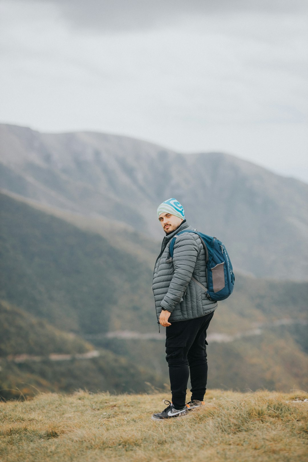 man in black jacket standing on top of mountain during daytime